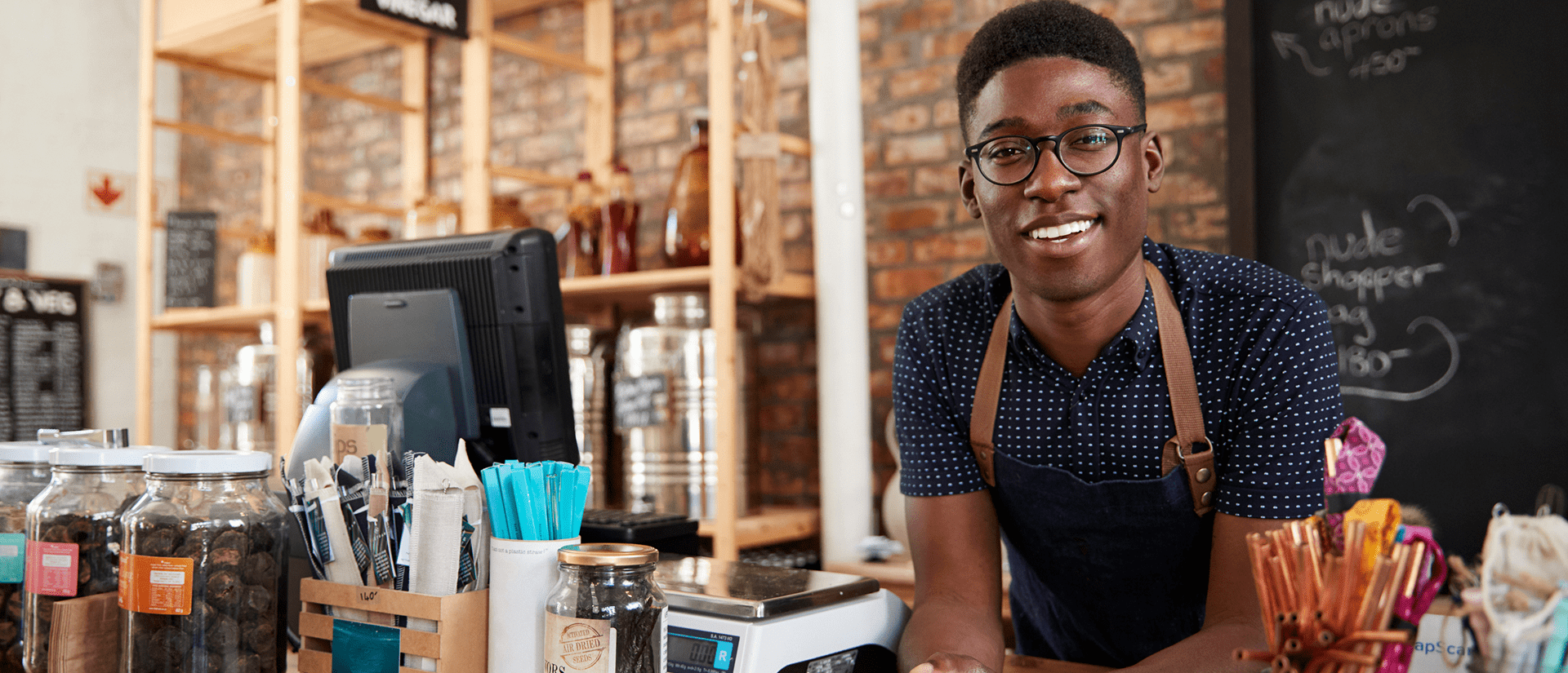 Smiling barista at a coffee shop counter.