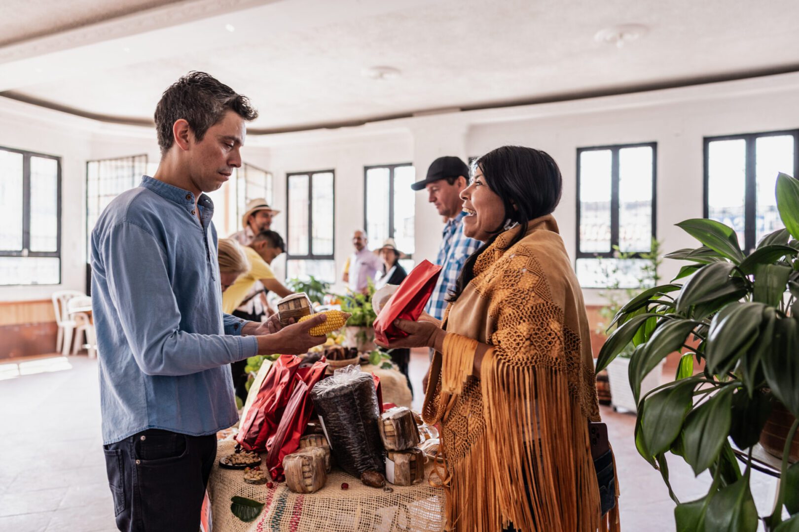People exchanging goods at indoor market stall.