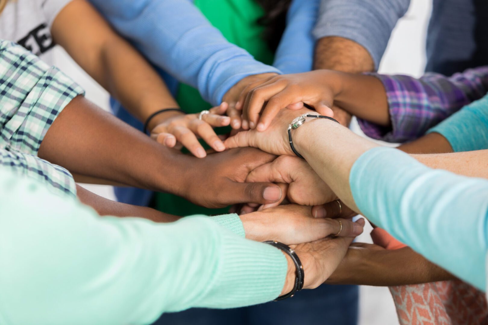 Diverse hands stacked in unity gesture.